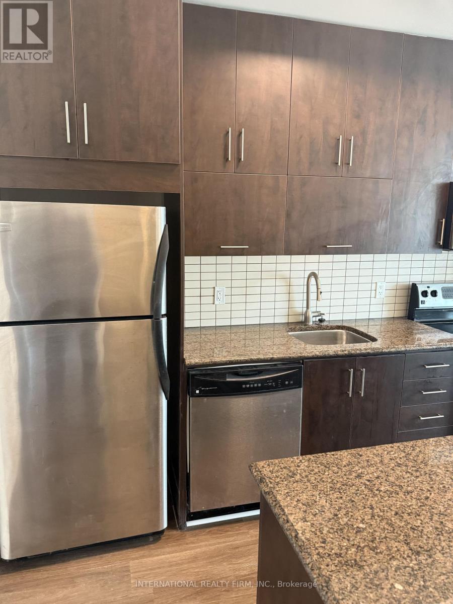A kitchen with a stainless steel refrigerator and wooden cabinets.