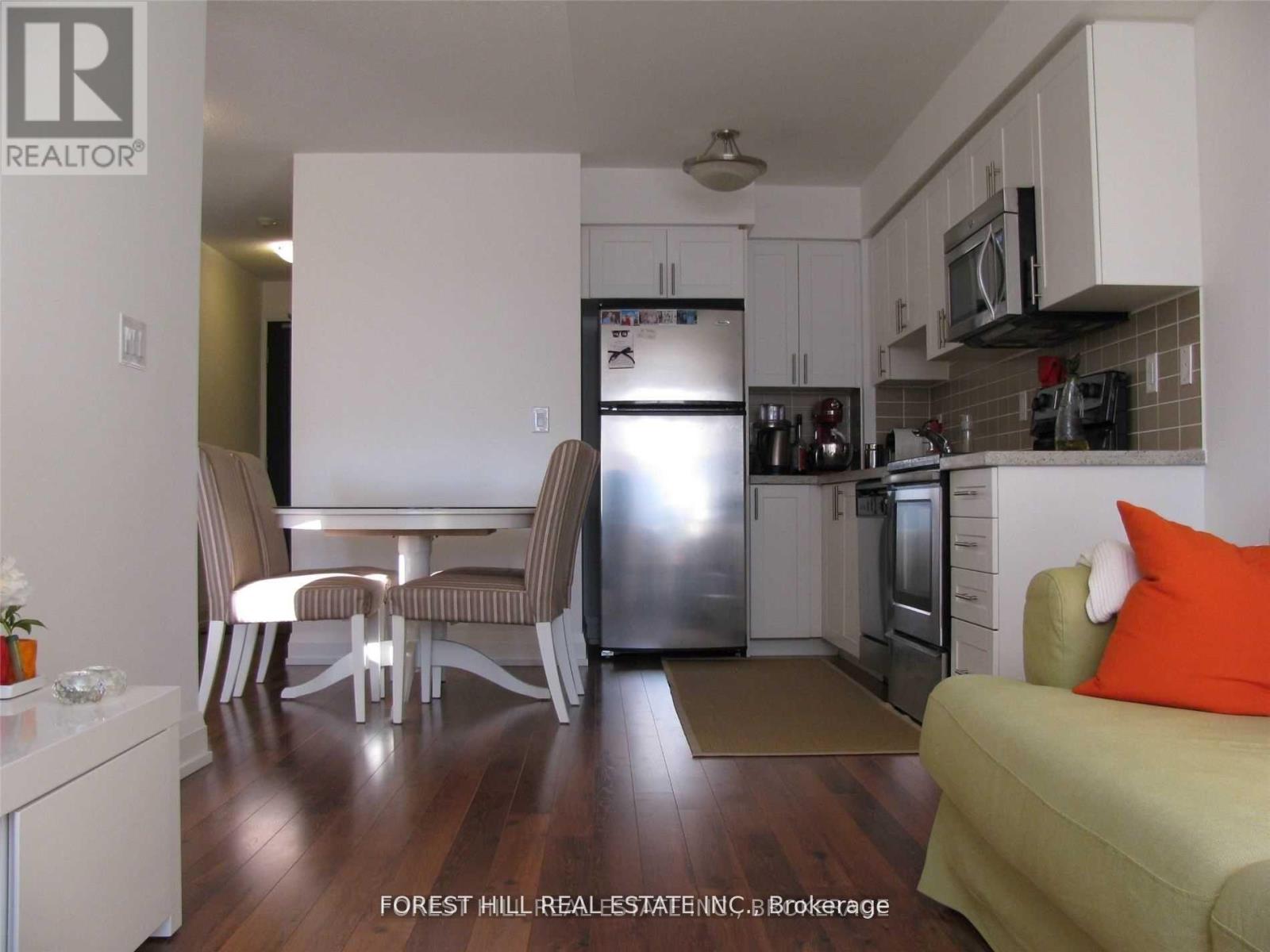A kitchen with a refrigerator, microwave, and oven.