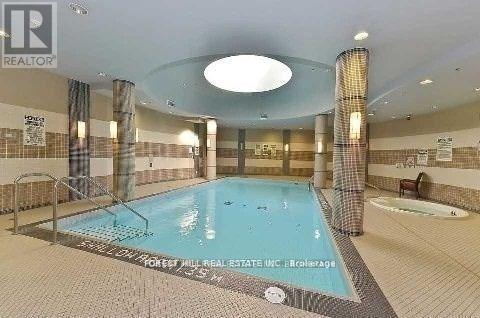 A large indoor swimming pool with a sign that reads "Pinecrest Real Estate Inc.".