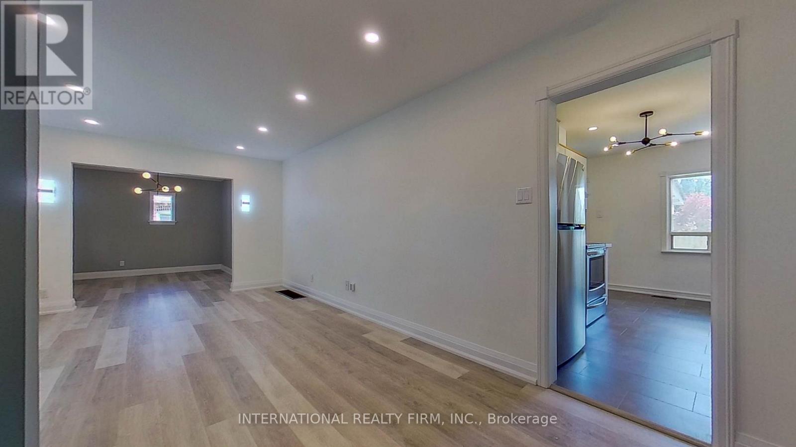 A spacious room with wooden flooring and a large window.