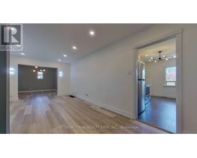A spacious room with wooden flooring and a large window.