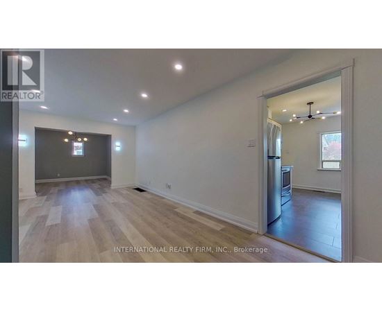 A spacious room with wooden flooring and a large window.
