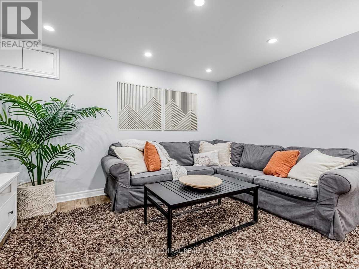 A living room with a grey couch, a coffee table, and a plant.