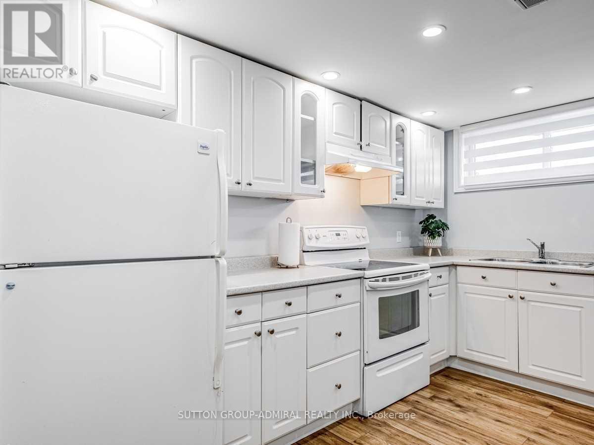 A white kitchen with a refrigerator, oven, and sink.