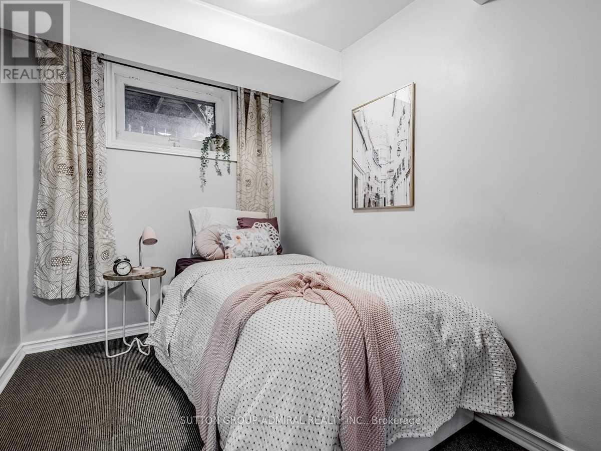 A bedroom with a bed covered in a white and pink comforter.
