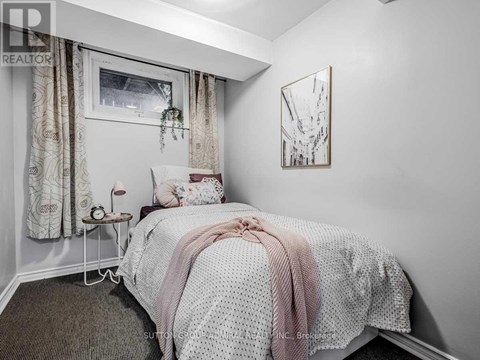 A bedroom with a bed covered in a white and pink comforter.