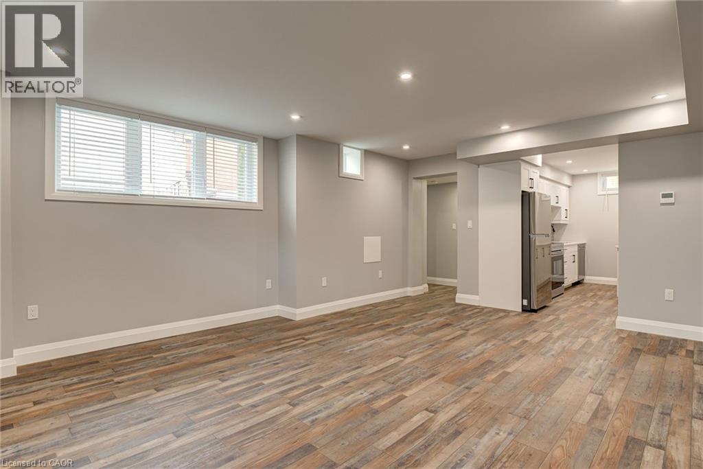 A spacious room with wood flooring and a refrigerator in the corner.