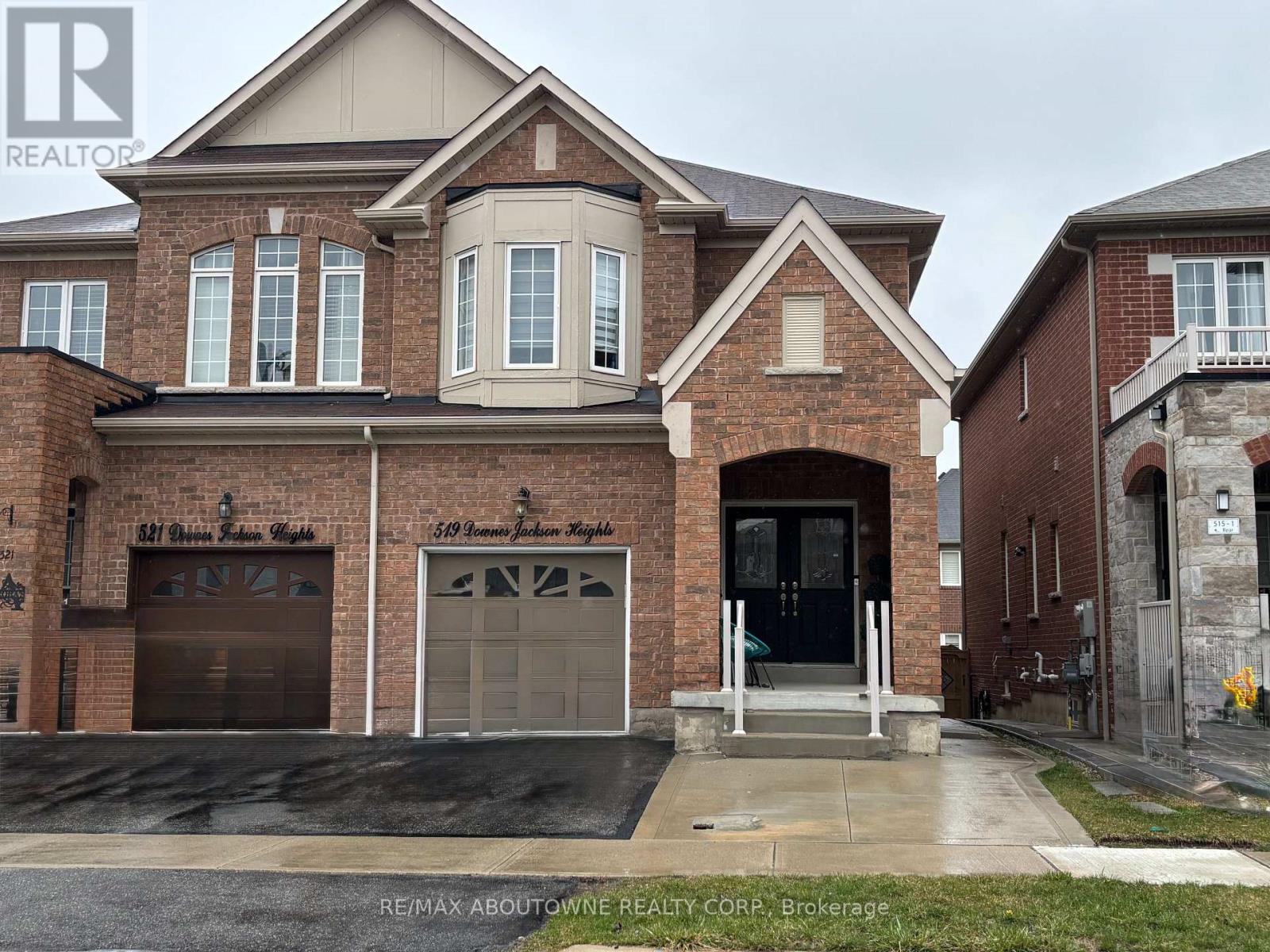 A large brick house with a garage door and a balcony.