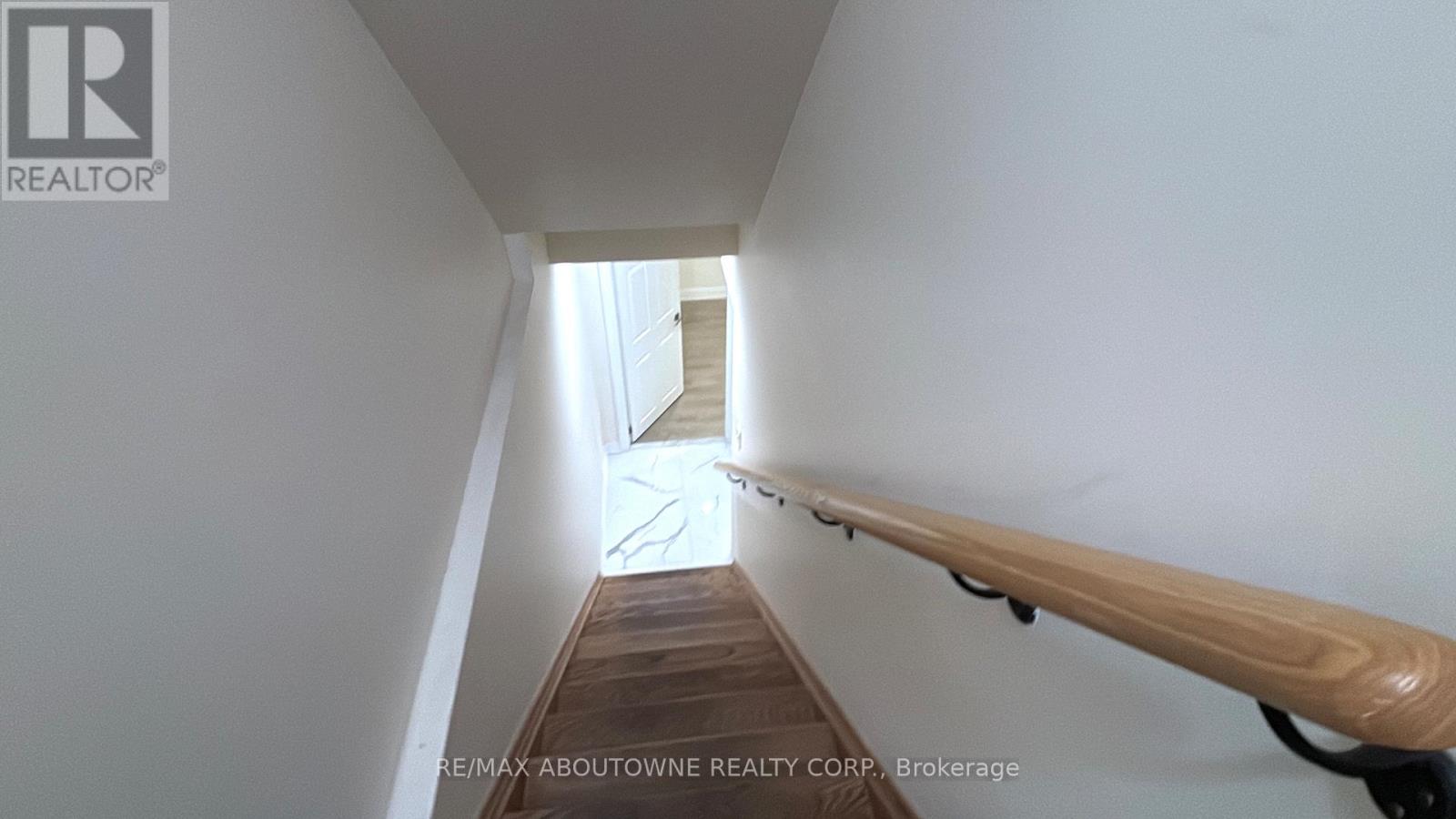 A hallway with a wooden railing and a staircase in the distance.