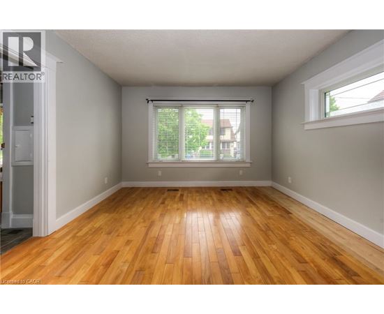 A room with wooden floors and a window with blinds.