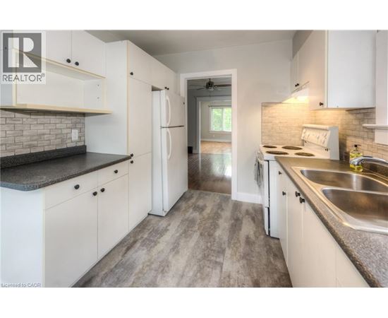 A kitchen with white cabinets and a brick backsplash.