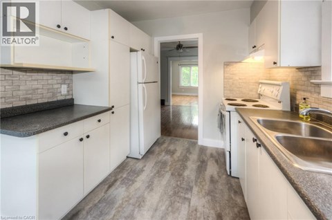 A kitchen with white cabinets and a brick backsplash.
