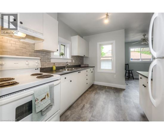 A kitchen with white cabinets and a white stove top oven.