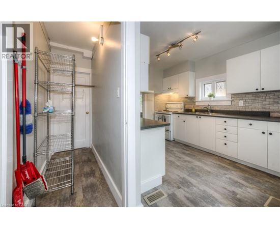 A white kitchen with a red broom in the foreground.
