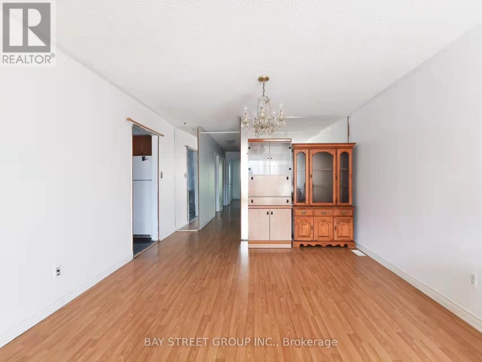 A spacious room with wooden floors and a chandelier.