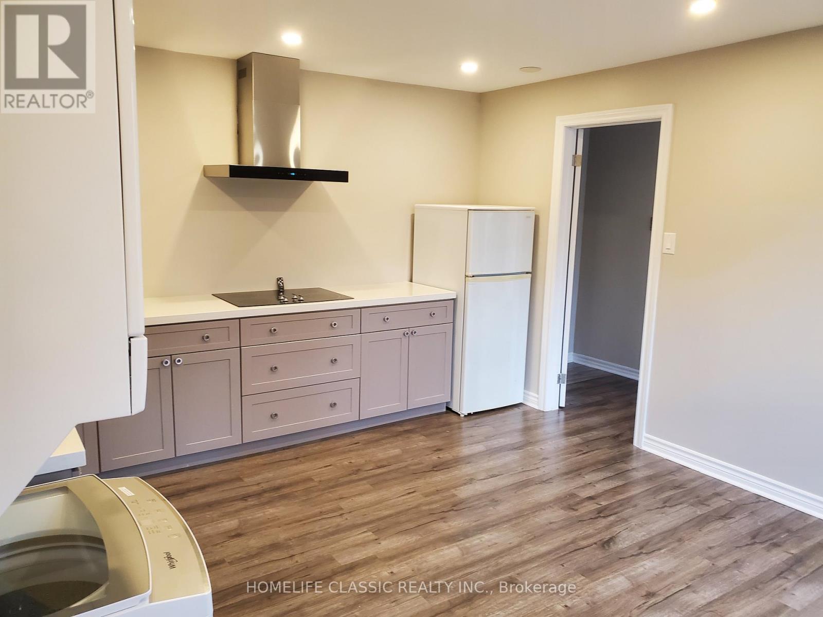 A kitchen with a sink, cabinets, and a refrigerator.