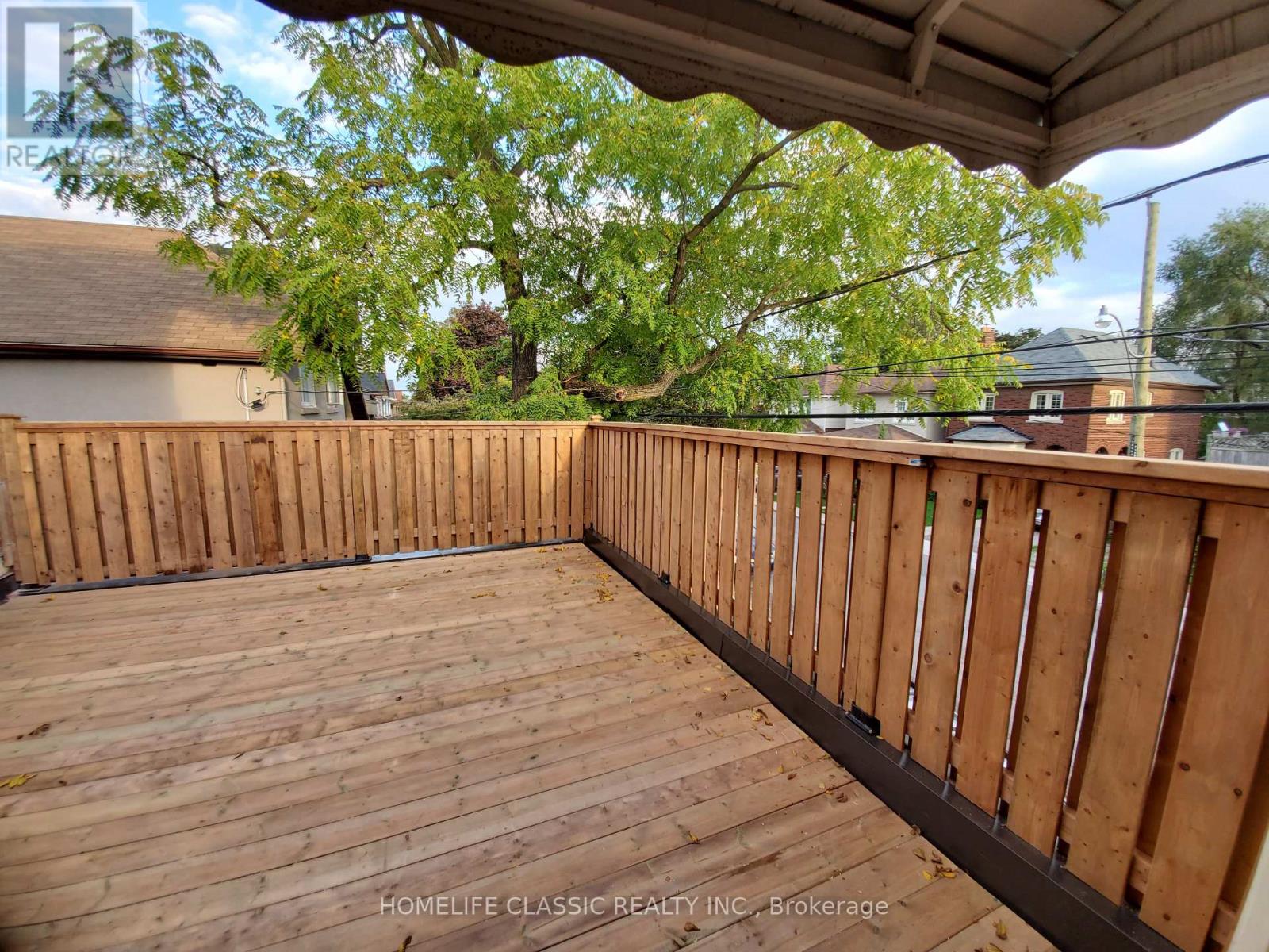 A wooden deck with a railing and trees in the background.