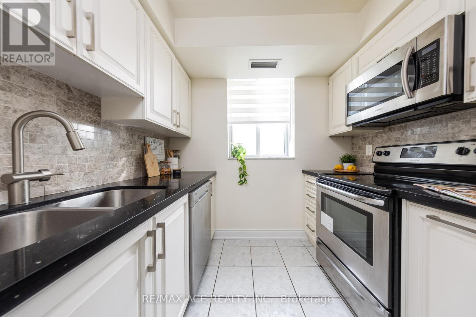 A kitchen with white cabinets and black countertops.