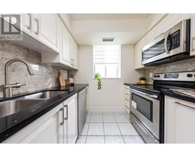 A kitchen with white cabinets and black countertops.