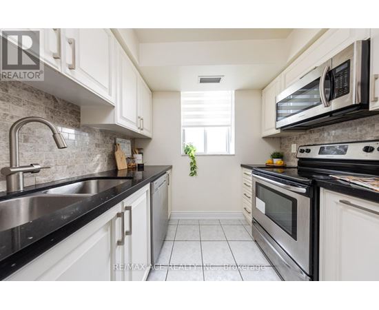 A kitchen with white cabinets and black countertops.