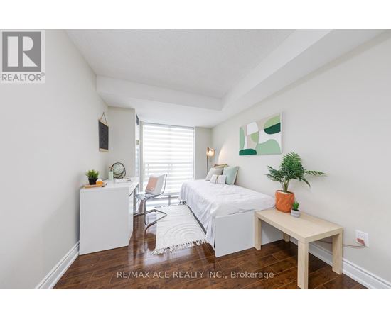 A bedroom with a bed, a chair, a table, and a plant.