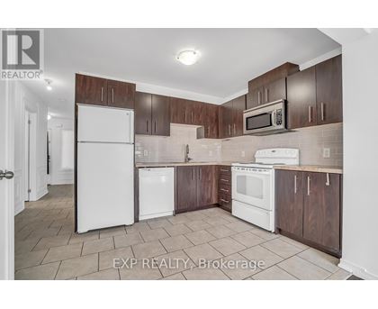 A kitchen with white appliances and brown cabinets.