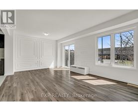 A room with white walls and wooden flooring, with a window showing a tree and a building outside.
