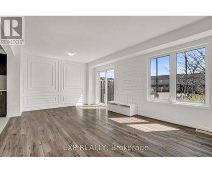 A room with white walls and wooden flooring, with a window showing a tree and a building outside.