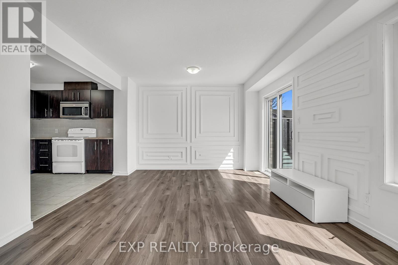 A spacious room with wooden flooring and white walls.