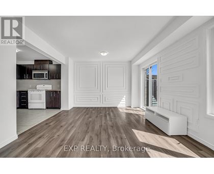 A spacious room with wooden flooring and white walls.
