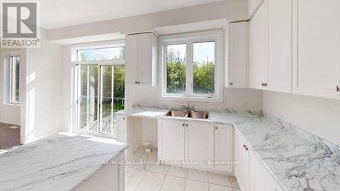 A kitchen with white cabinets and marble countertops.