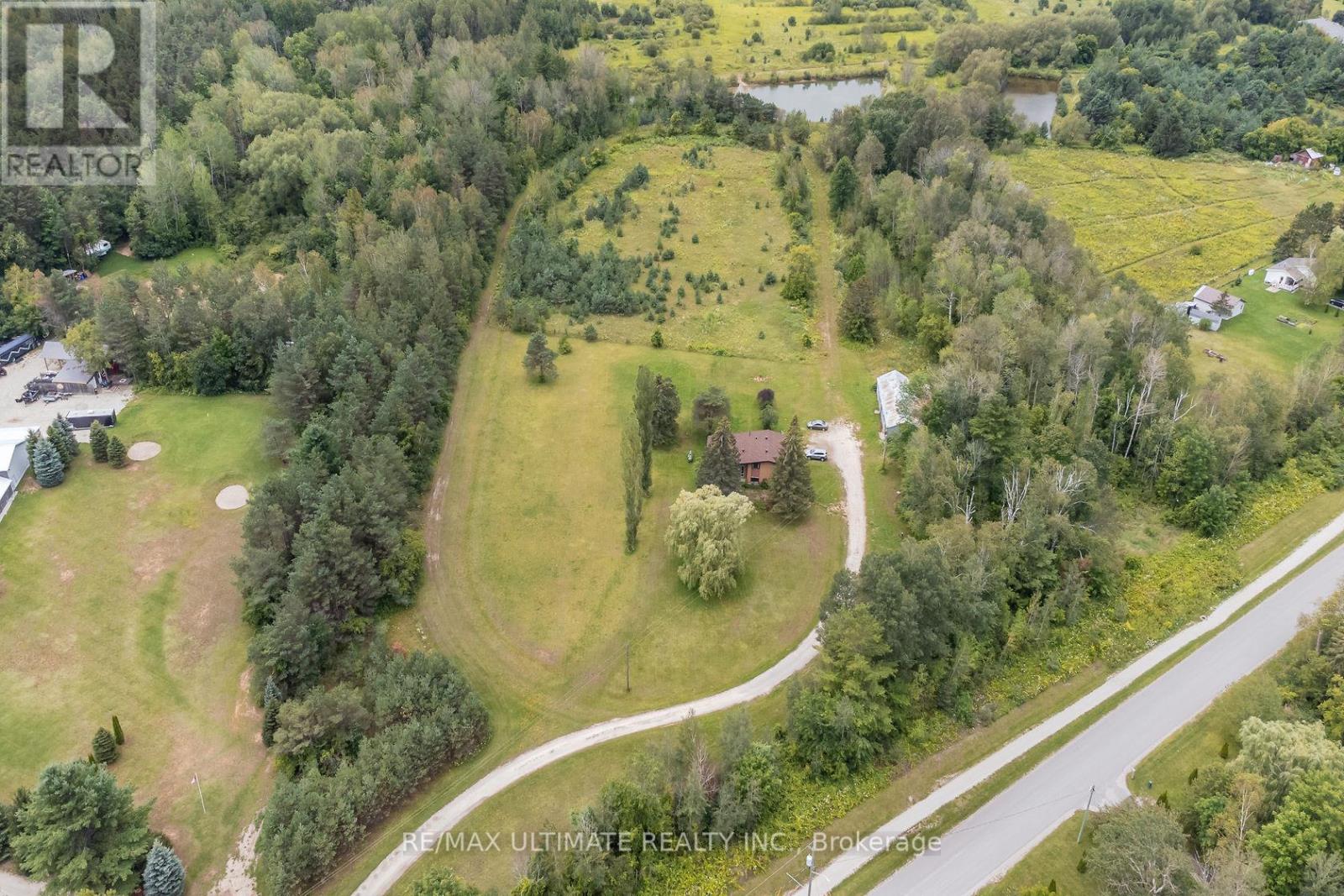 A bird's eye view of a property with a house, trees, and a road.