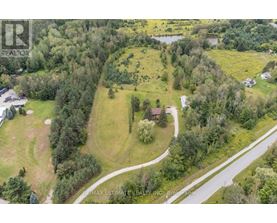 A bird's eye view of a property with a house, trees, and a road.