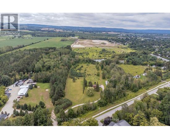 A bird's eye view of a property with a large open field and a building complex.