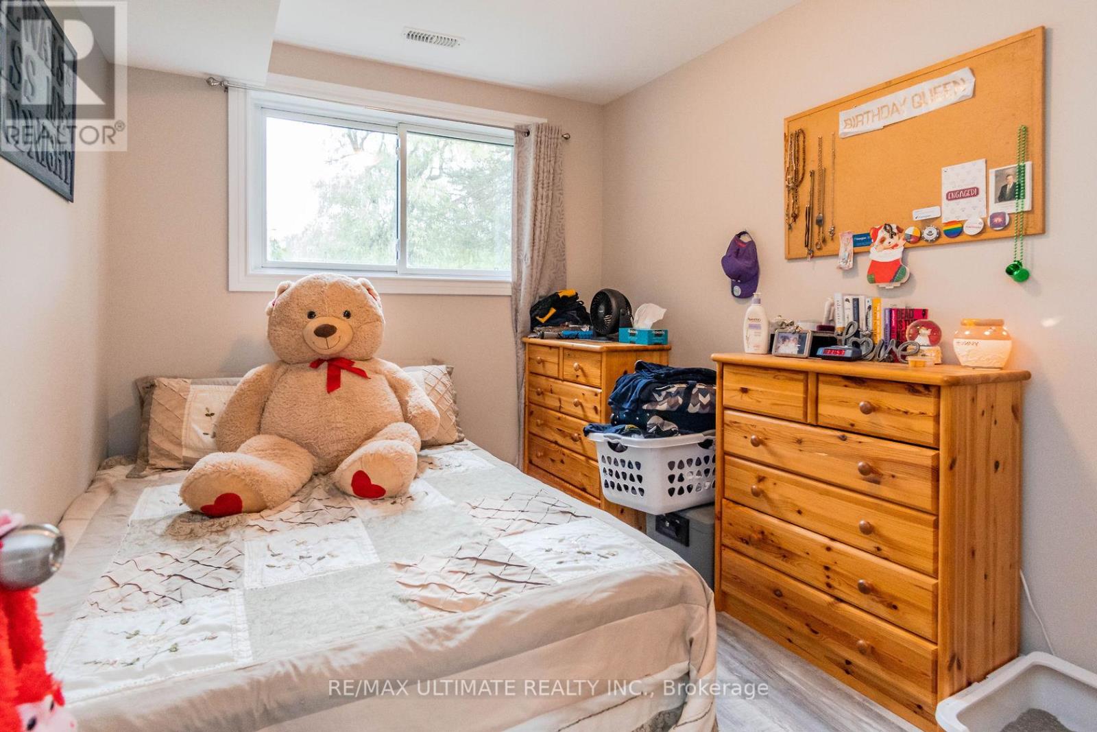 A bedroom with a bed, a dresser, and a window.
