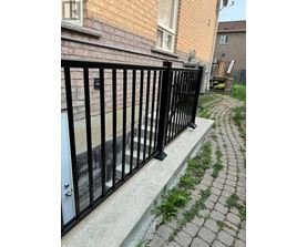 A black metal fence is in front of a brick building.