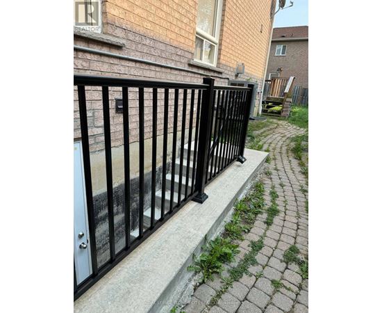 A black metal fence is in front of a brick building.