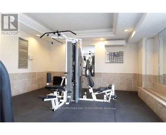 A home gym with a weight machine, bench, and mirror.