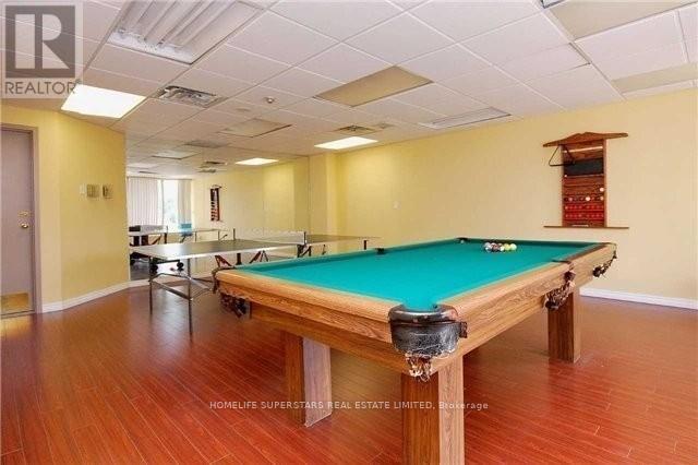 A pool table in a room with wooden flooring and a white ceiling.