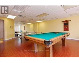 A pool table in a room with wooden flooring and a white ceiling.