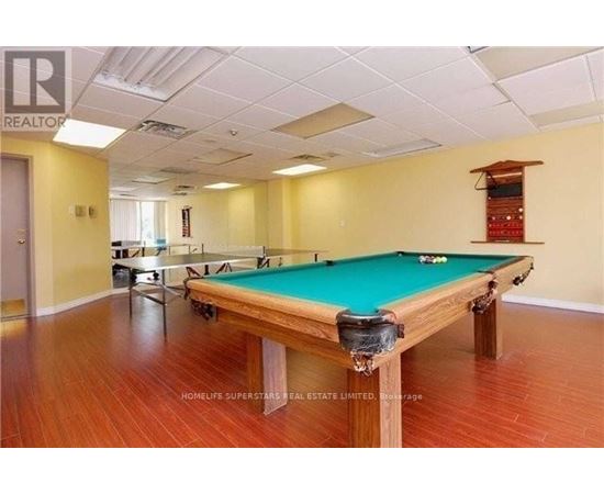 A pool table in a room with wooden flooring and a white ceiling.