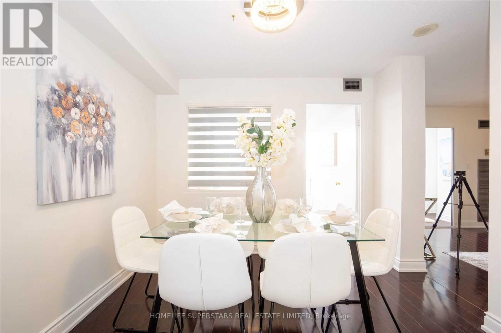 A dining room with a glass table and white chairs.