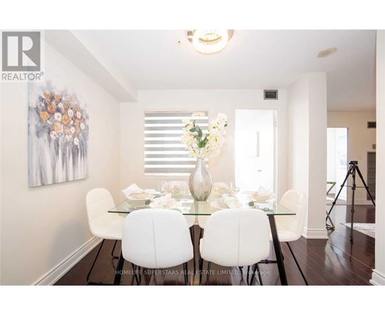 A dining room with a glass table and white chairs.