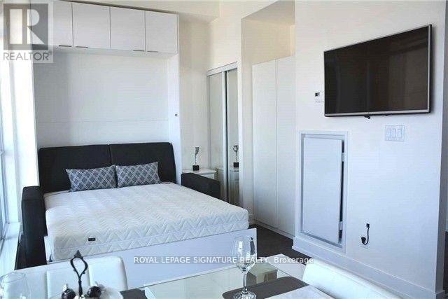 A bedroom with a bed, a television, and a cabinet.