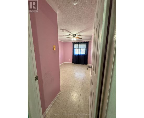 A room with a ceiling fan and a door leading to another room.
