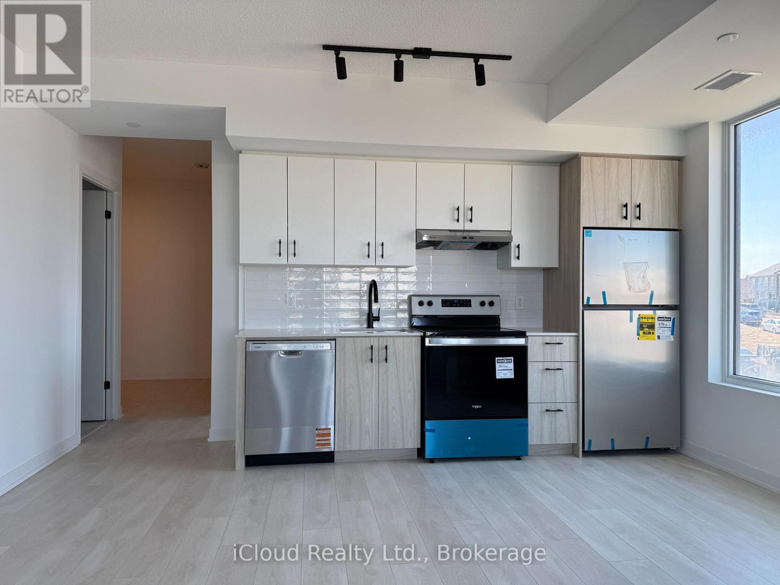 A kitchen with white cabinets and a stainless steel refrigerator.