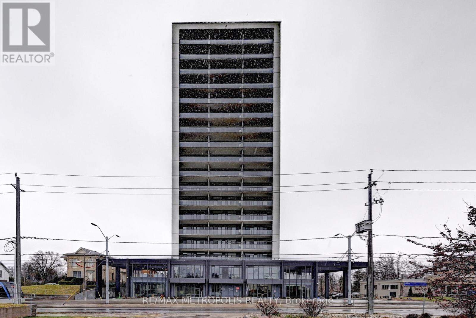 A tall building with a grey facade stands in the middle of a street.