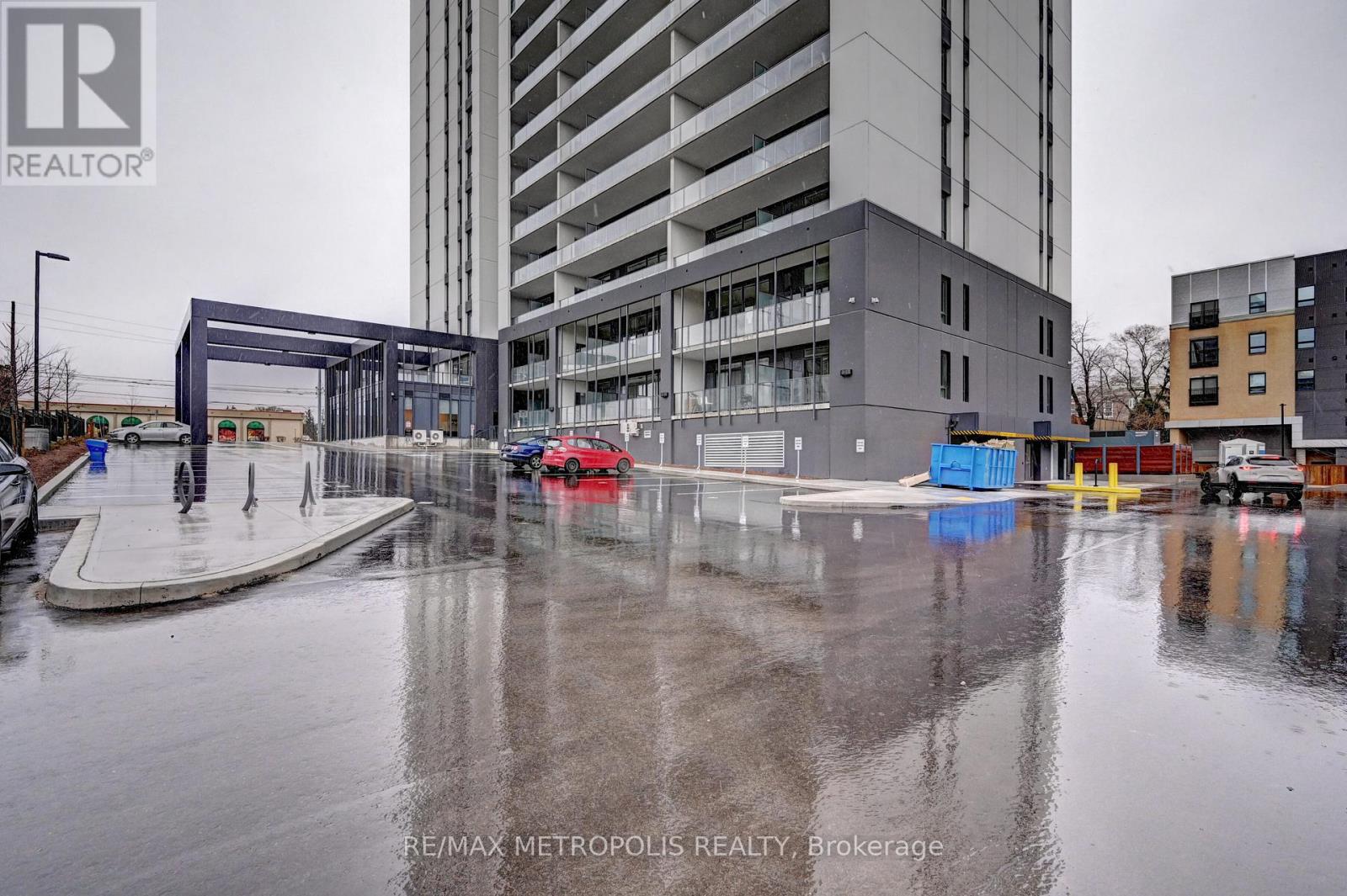 A wet parking lot with cars and a building in the background.