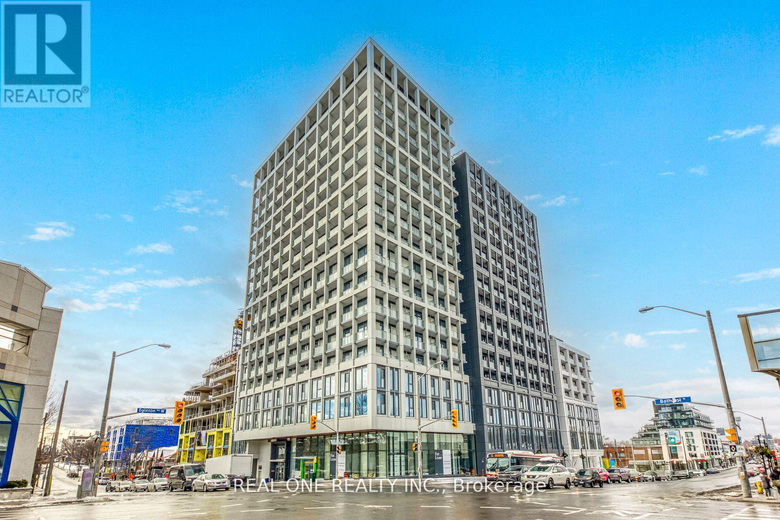 A tall building with a glass facade stands in the middle of a city street.