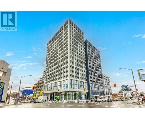 A tall building with a glass facade stands in the middle of a city street.